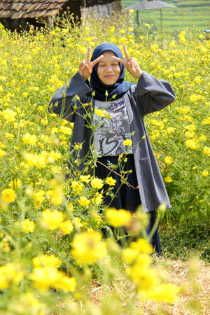 portrait of an asian woman posing in a yellow ray flower garden. Enjoy a weekend getaway on nature tourismの写真素材