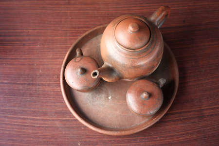 kettles and glasses handmade with clay materials. traditional Javanese kitchen tools used for warm drinks. Indonesian red kitchen utensil on a wooden backgroundの写真素材