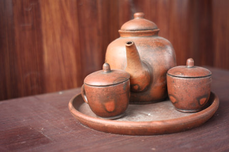 kettles and glasses handmade with clay materials. traditional Javanese kitchen tools used for warm drinks. Indonesian red kitchen utensil on a wooden backgroundの写真素材