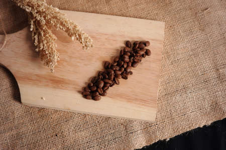 close up of coffee beans and wheat on wooden background and burlap sack texture. still life photos...