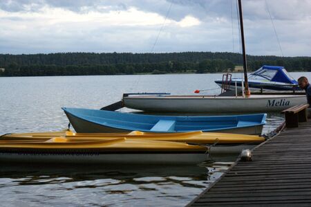 wooden bridge on the lake moored boats sailboat cloudy weather on Masuria in Polandの写真素材