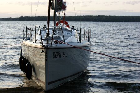 sunset sailing yacht sailboat moored on a dead lake approaching on boardの写真素材