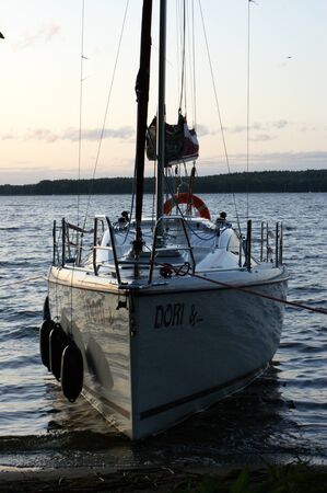 sunset sailing yacht sailboat moored on a dead lake approaching on boardの写真素材