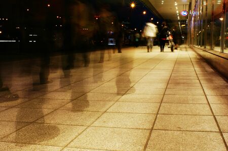 a group of people walking on the sidewalk promenade long exposure at night shoppingの写真素材