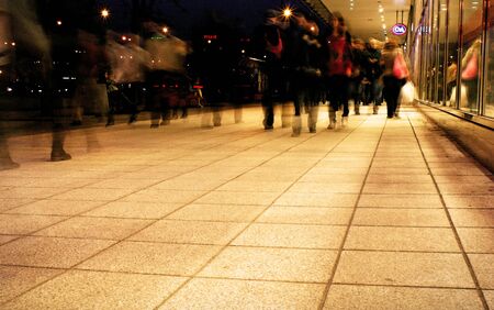a group of people walking on the sidewalk promenade long exposure at night shoppingの写真素材