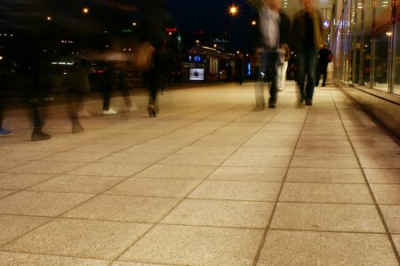 a group of people walking on the sidewalk promenade long exposure at night shoppingの写真素材