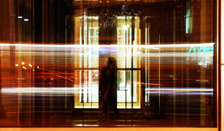 long exposure time reflected in the glass in the city cars are moving fast colorful lightsの写真素材