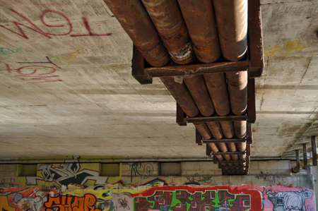 underpass under the bridge next to the stream of the river old rusty pipesの写真素材