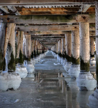 frozen sea ocean water under the bridge pier balls poles in a rowの写真素材
