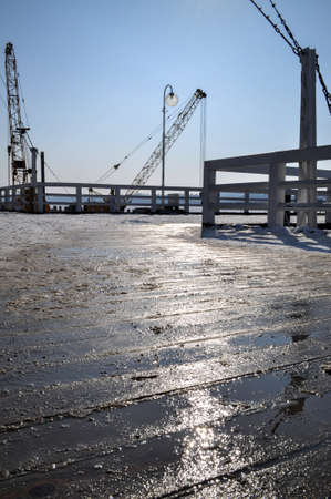 pier under construction oil rig cranes light reflection in wooden wet planks platform sunlightの写真素材