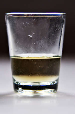 a glass of whiskey transparent yellow golden drink with lightの写真素材