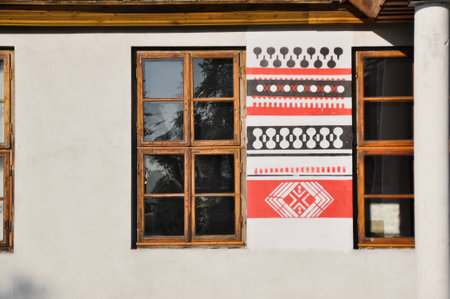 old antique decorative window in folk style, folk wooden frame, painted wall white black and redの写真素材