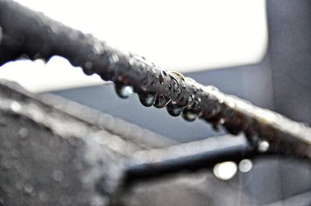 Water droplets hang from a rusty metal railing