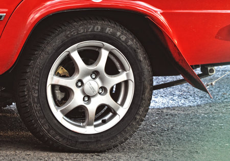 The rim and wheel of a vintage old red sports car