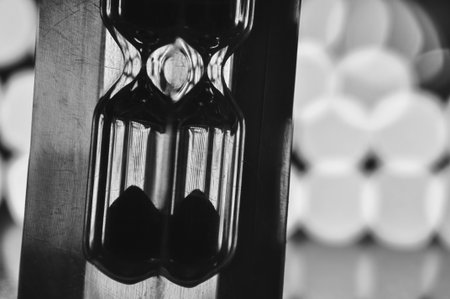 A black-and-white hourglass close-up measuring time with flowing sand