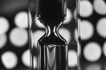 A black-and-white hourglass close-up measuring time with flowing sand