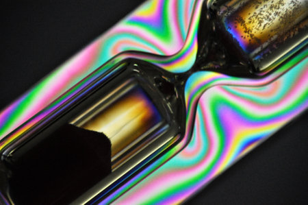 A colorful rainbow hourglass measuring time against a black backgroundの写真素材