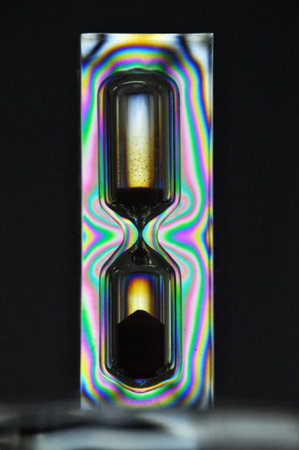 A colorful rainbow hourglass measuring time against a black background