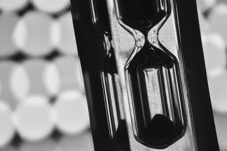 A black-and-white hourglass close-up measuring time with flowing sand