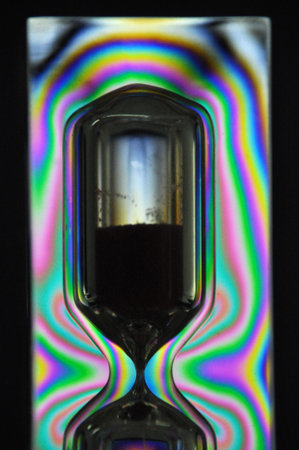 A colorful rainbow hourglass measuring time against a black background
