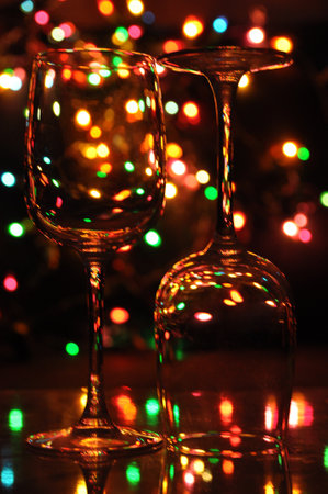 transparent wine glasses, with colorful Christmas lights in the backgroundの写真素材