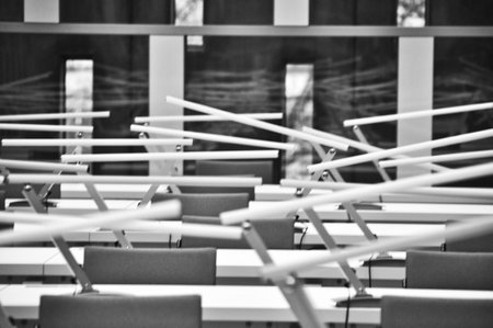 Rows of white desks illuminated by modern lamps in the library reading roomの写真素材