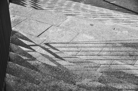 Monochromatic photo of stairs, close-up of shadows cast on the stairs from the railingの写真素材