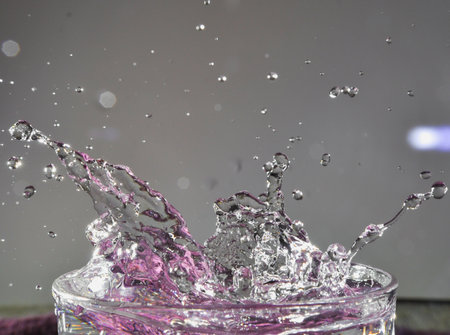 A drop splashing in purple water, falling into the water on a white background sparking