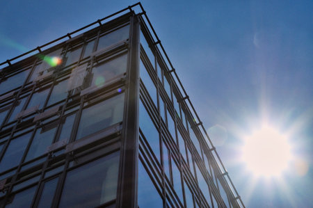 blue glass wall of office building mirror reflection cityscape blinding sunの写真素材