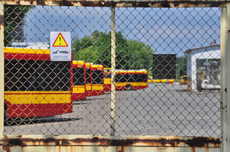 Warsaw city bus depot old rusty fence yellow red buses parked in a rowの写真素材