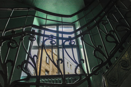 Interior of a tenement building with a window, green staircase with an ornate decorative metal railing abandoned buildingの写真素材