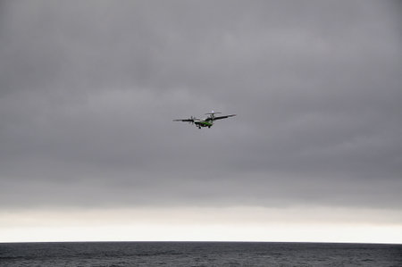 Small prop plane landing over the sea.;