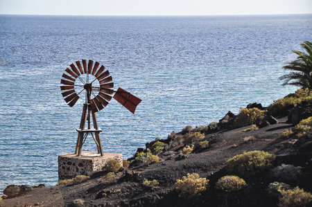 Wooden windmill on a rocky sea cliffの写真素材