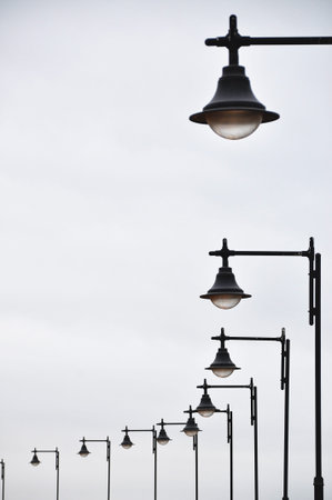 Row of black street lamps against cloudy sky;の写真素材