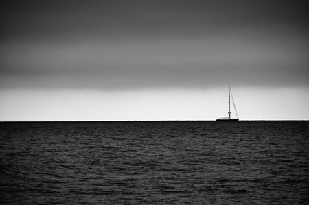Lone sailboat on calm sea under cloudy sky;の写真素材