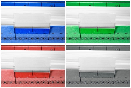 hanging file folders in blue, green, red and grey with blank labelsの写真素材