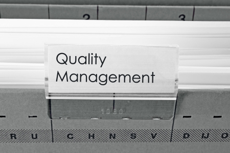 grey hanging file folder labeled with Quality Managementの写真素材