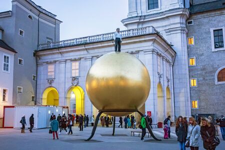 Salzburg, Austria - December 31, 2013: Golden sphere with man standing on it at Kapitelplatz at night - near the Cathedral of Salzburg.のeditorial素材