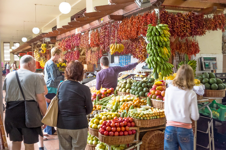 Funchal, Portugal - June 3, 2013: Market in Funchal, Madeira. Booth with merchant trading fruits and spices with tourists.のeditorial素材
