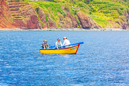 Calheta, Madeira - June 8, 2013: Three friendly fishermen on yellow motorboat offshore of Calheta in the west of Madeira island.のeditorial素材