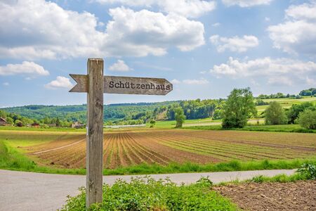 Signpost labeled with rifle associations clubhouse - in german language (Schuetzenhaus) - rural landscape in the backgroundの写真素材