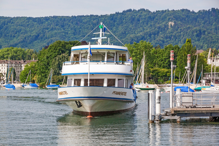 Zurich, Switzerland - June 10, 2017: Excursion boat "Pfannenstiel" arriving at shipping pier Burkliplatz. Western bank of Lake Zurich, Mythenquai / Enge in background.のeditorial素材