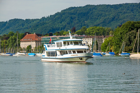 Zurich, Switzerland - June 10, 2017: Excursion boat "Pfannenstiel" arriving at shipping pier Burkliplatz. Western bank of Lake Zurich, Mythenquai / Enge in background.のeditorial素材