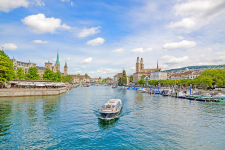 Panoramic view of historic Zurich city center with famous Grossmunster, Fraumunster, St. Peter church. Cruise vessel on river Limmat in front on a sunny day with clouds in summer, Canton of Zurich, Lake Zuerich, Switzerlandの写真素材
