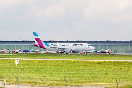 Stuttgart, Germany - April 29, 2017: Airbus A319 airplane from Eurowings at ground (airport Stuttgart) on its way to take off - green meadow with fence in front, hangar in backgroundのeditorial素材