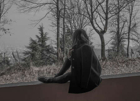 Girl looking up at the countryside and sitting on the parapetGirl looking up at the countryside and sitting on the parapetの写真素材