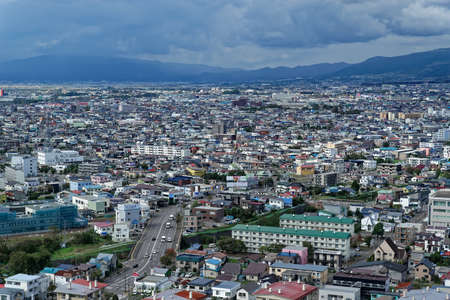 Daytime view of the suburbs of Hakodate, in northern Japan, stretching out towards low hills and clouds in the distanceのeditorial素材