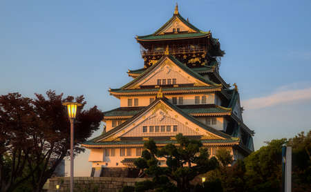Osaka, Japan - October 31 2020: Late afternoon view of Osaka Castle, tinted orange by the setting sun and under a blue skyのeditorial素材