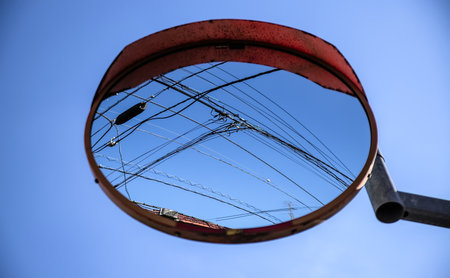 Looking up at a round convex roadside mirror reflecting a blue sky and elevated power lines on a clear day in west Tokyoの写真素材