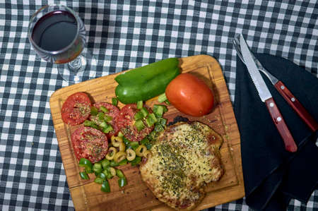 Milanese cheese with sliced tomatoes with olives with green pepper cubes on wooden boardの写真素材